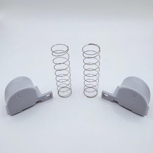 May include: Two grey plastic pieces with the letters 'L' and 'R' on them, and two silver springs.