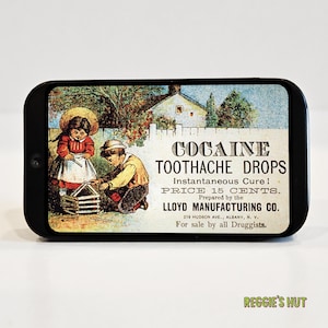 May include: A black rectangular tin with a vintage advertisement for "Cocaine Toothache Drops." The label features an illustration of two children and text that reads "Instantaneous Cure!" and "Price 15 Cents."
