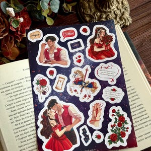 May include: A sticker sheet with illustrations of couples, roses, and a carousel. The stickers have a dark blue background with white borders. Some stickers have text, including the word "Crimson".
