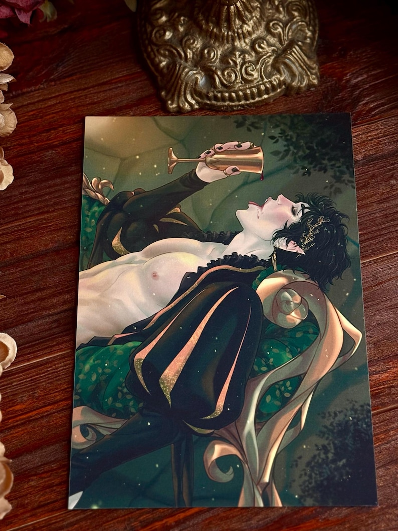 May include: An art print featuring a person reclining on a green and gold patterned chaise lounge, drinking from a gold goblet. The person is wearing a black outfit with gold accents. The background is a dark, stylized forest scene.