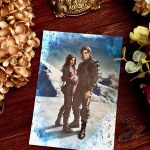 Può includere: Una carta stampata raffigurante una coppia vestita di scuro sullo sfondo di un paesaggio montuoso innevato. L'uomo, con i capelli lunghi, indossa un'uniforme nera. La donna tiene in mano un piccolo animale. Lo sfondo ha un effetto acquerello blu e bianco.