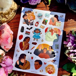 Può includere: Un foglio di adesivi con varie illustrazioni tra cui personaggi in abiti formali, una coppia che si bacia, una persona con la bocca rossa, una bambola, una cassetta, un pipistrello, un cuore, un bicchiere di vino rosso e il testo Unholy Family e You Can Rest.