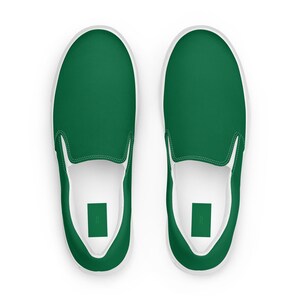 May include: A pair of green slip-on sneakers. The shoes have a solid green upper with a white sole and white trim. The design is simple and modern, suitable for casual wear.