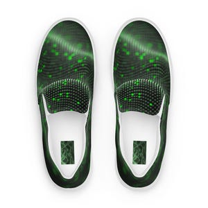 May include: Pair of slip-on sneakers with a black and green digital pattern. The design features a wavy, dotted texture with scattered green dots. The shoes have white soles and a white interior.