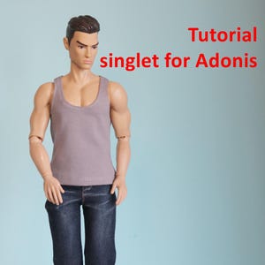 Puede incluir: Una muñeca con un top sin mangas gris y vaqueros azul oscuro, con zapatos blancos. El texto "Tutorial singlet for Adonis PDF" está en rojo. La muñeca tiene el pelo castaño corto y está sobre un fondo azul claro.