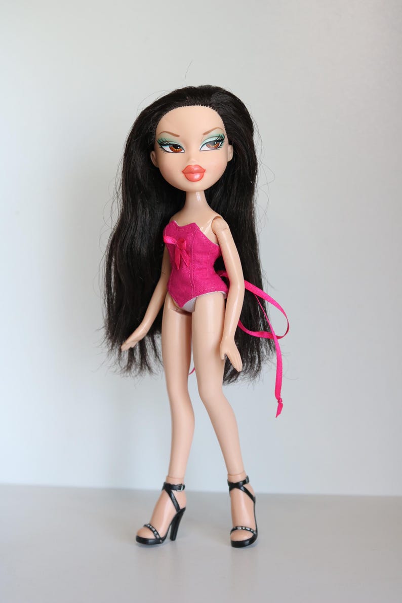 May include: A pink and black doll with long black hair wearing a pink corset and black high heels.