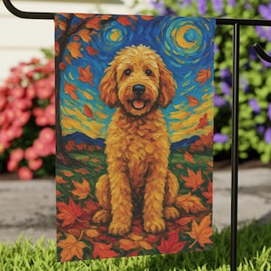 May include: A garden flag featuring a golden doodle dog sitting in a field of autumn leaves. The background has a blue sky with a starry night design. The dog is surrounded by orange and red leaves.