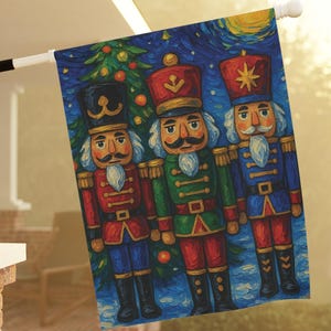 May include: A decorative outdoor flag featuring three nutcracker soldiers in vibrant colors. The flag has a dark blue background with a Christmas tree and a starry night sky. The nutcrackers are in red, green, and blue uniforms.