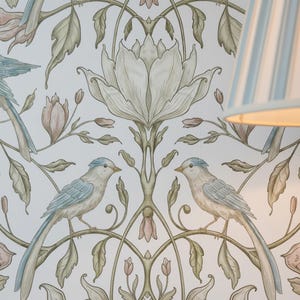 May include: Wallpaper featuring a repeating pattern of symmetrical floral motifs and two birds facing each other. The design includes muted green leaves, pale pink flower buds, and large central white blossoms on a light background.