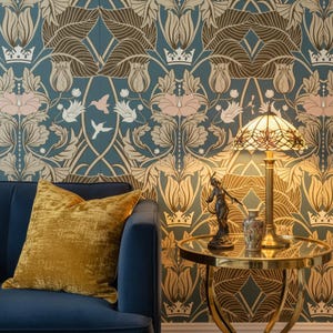 Peut inclure: Intérieur de salon avec un canapé en velours bleu et un coussin en velours doré. Une petite table ronde supporte une lampe avec un abat-jour en vitrail, une petite statue et un vase décoratif. Le papier peint présente un motif floral.