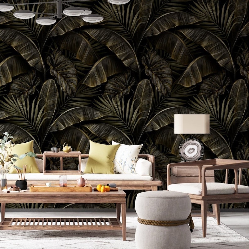 May include: A living room scene featuring a dark, tropical-themed wallpaper with large, detailed palm leaves in shades of gold and brown. The room includes wooden furniture, a white rug, and decorative pillows, creating a cohesive and stylish interior design.