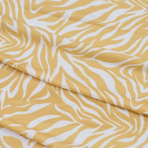 May include: A yellow and white fabric with a zebra print pattern.