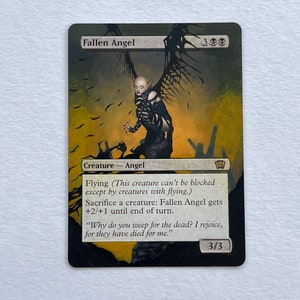 May include: A Fallen Angel card featuring a dark illustration of a bald, winged figure in black armor against a yellow and black background. The card text includes "Creature - Angel" and game instructions.