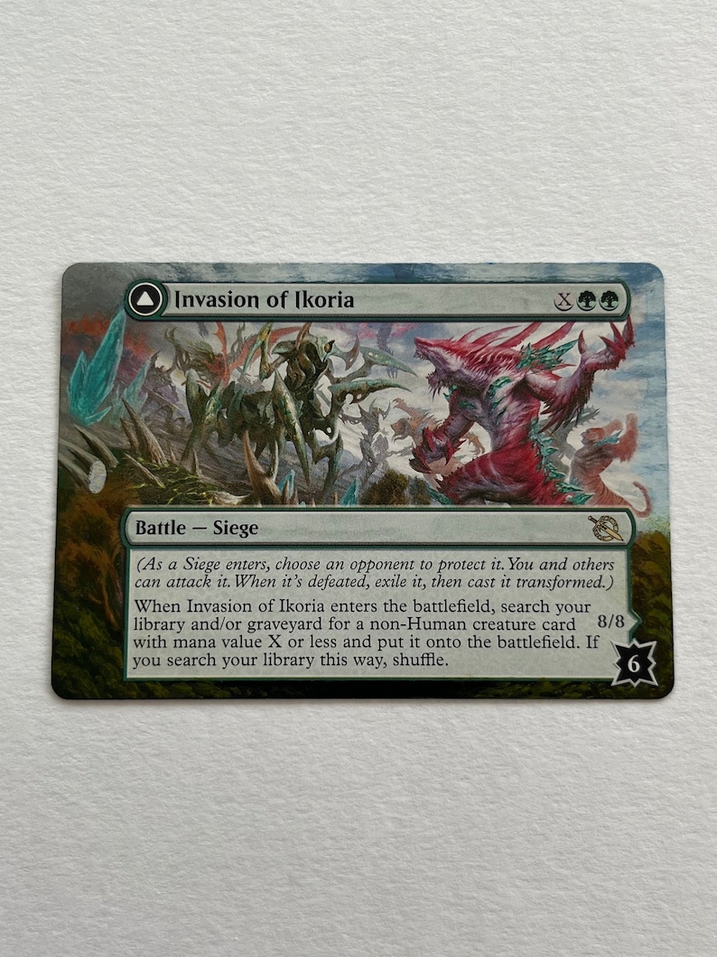 May include: A green, blue, and red fantasy creature card with the text "Invasion of Ikoria" and "Battle - Siege". The card has a green, blue, and red background with a white border. The card has a white border and a black symbol in the bottom right corner.