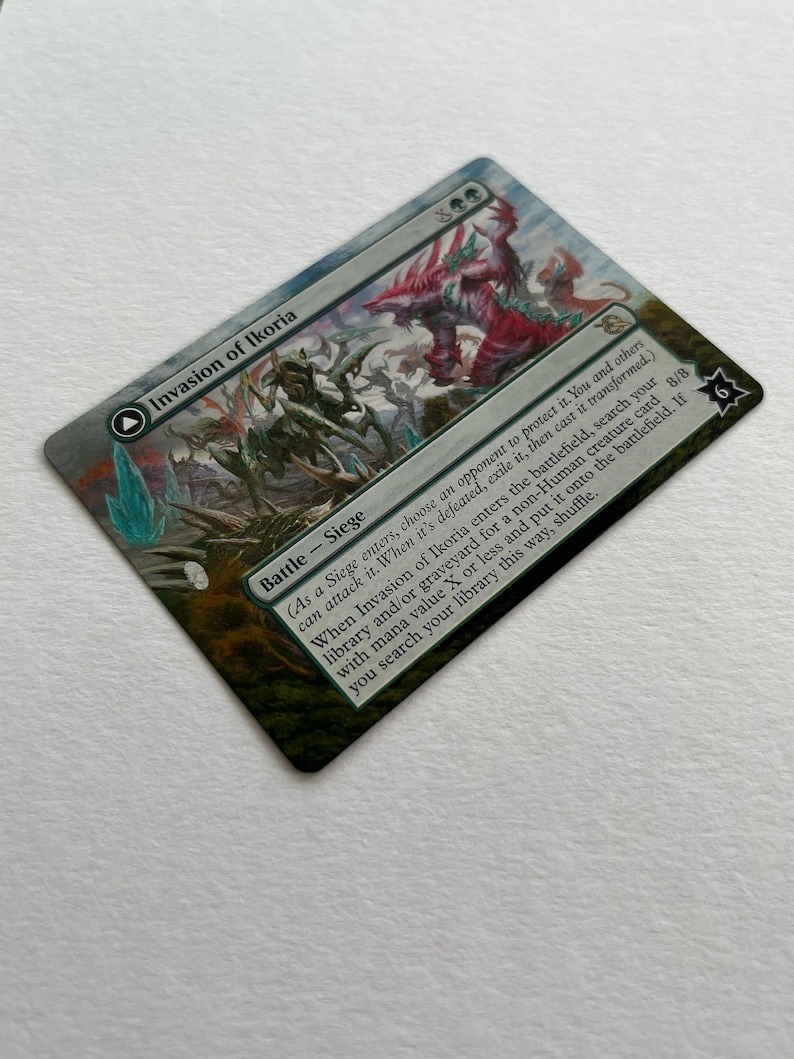 May include: A Magic: The Gathering card called "Invasion of Ikoria" with a green, blue, and red color scheme. The card features a large, multi-headed creature with a red, green, and blue color scheme. The card text reads: "(As a Siege enters, choose an opponent to protect it. You and others can attack it. When it's defeated, exile it, then cast it transformed.) When Invasion of Ikoria enters the battlefield, search your library and/or graveyard for a non-Human creature card with mana value X or less and put it onto the battlefield. If you search your library this way, shuffle."