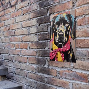 May include: A colorful painting of a black dog wearing a pink and yellow bow tie. The painting is on a canvas and is hanging on a brick wall.