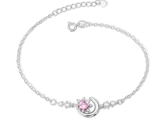 May include: A silver bracelet with a crescent moon charm and a sun charm with a pink gemstone. The bracelet has a delicate chain and a lobster clasp.