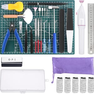 Könnte beinhalten: Ein umfassendes Set für Nagelkunst und Bastelarbeiten mit einer grünen Schneidematte, Zangen mit blauen Griffen, einem weißen elektrischen Nagelfräser, einem Metalllineal, verschiedenen Feilen, einem kleinen Hammer, einem schwarzen OPI-Block und Fingerlingen.