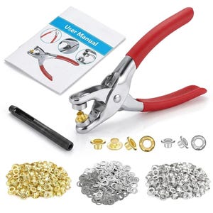 May include: A metal eyelet setting tool with red rubberized handles, a black cylindrical punch tool, a user manual, and three piles of gold and silver metal eyelets and washers for fabric and leather crafting projects.