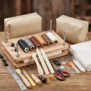 May include: A bookbinding kit featuring a wooden press with metal hardware, two beige zippered pouches, six spools of thread, bone folders, a metal ruler, brushes, awls, scissors, needles, a thimble, and paper stacks for crafting and repair projects.