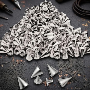 May include: A large collection of silver-colored metal cone-shaped studs with screw-back fasteners. The pile includes numerous pointed spikes and matching circular threaded bases, with several individual pieces displayed separately in the foreground.