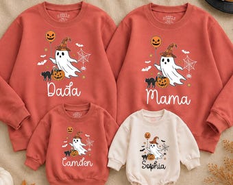 May include: Two rust-colored sweatshirts, one smaller rust-colored sweatshirt, and one cream-colored long-sleeve bodysuit. Each garment features a graphic of a ghost wearing a witch hat, a pumpkin, a black cat, and text reading Dada, Mama, Camden, or Sophia.