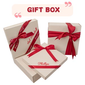 May include: Several cream-colored gift boxes tied with red satin ribbons. The boxes have the text "Gift Box" at the top. Some ribbons have the text "Syd Marshall" and "Phillips".