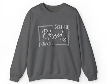 Peut inclure: Un sweat-shirt gris foncé avec le texte "GRATEFUL Blessed THANKFUL" en lettres blanches dans un cadre blanc avec un petit cœur.