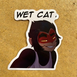 May include: A sticker featuring a cartoon character with black hair and a red mask. The character is wearing a white tank top and has a mischievous expression. The text "WET CAT." is printed above the character.
