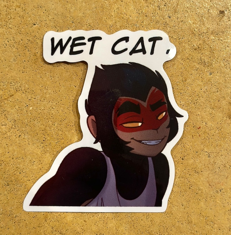 May include: A sticker featuring a cartoon character with black hair and a red mask. The character is wearing a white tank top and has a mischievous expression. The text "WET CAT." is printed above the character.