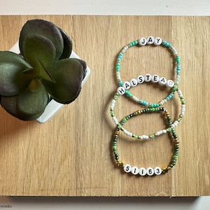 Puede incluir: Tres pulseras de cuentas con cuentas verdes, blancas y azules. Las pulseras deletrean los nombres "JAY", "HALSTEAD" y "51163".