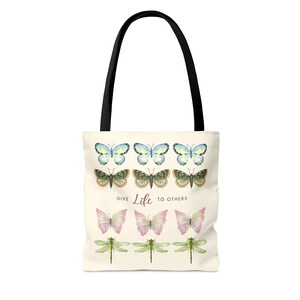 Vintage butterfly and dragonfly AOP Tote Bag! The tote bag has 3 times 3 Butterflies in a row in colours yellow-blue, green, yellow-pink, and 1 time dragonflies in light green. In the middle is a saying: Give live to others.