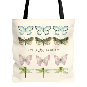 Zoomed in vintage butterfly and dragonfly AOP Tote Bag! The tote bag has 3 times 3 Butterflies in a row in colours yellow-blue, green, yellow-pink, and 1 time dragonflies in light green. In the middle is a saying: Give live to others.