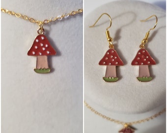 May include: A gold necklace and earrings set featuring a red and white mushroom charm. The mushroom has white dots on the top and a green stem.