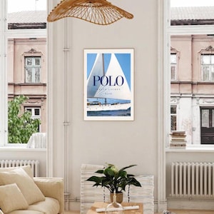 Peut inclure: Une affiche encadr&eacute;e avec un voilier blanc sur une &eacute;tendue d'eau bleue. L'affiche porte le texte "POLO RALPH LAUREN BLUE" en lettres bleues.