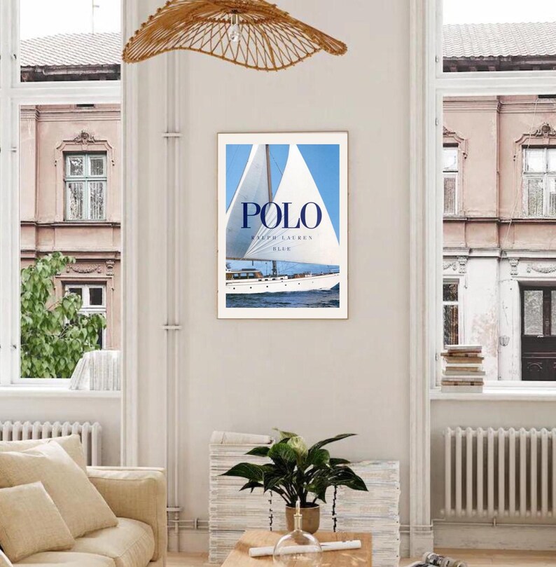 Peut inclure: Une affiche encadr&eacute;e avec un voilier blanc sur une &eacute;tendue d'eau bleue. L'affiche porte le texte "POLO RALPH LAUREN BLUE" en lettres bleues.