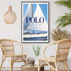 Peut inclure: Une affiche encadr&eacute;e avec un voilier bleu et blanc sur une mer bleue avec le texte "POLO RALPH LAUREN BLUE" en bleu marine.