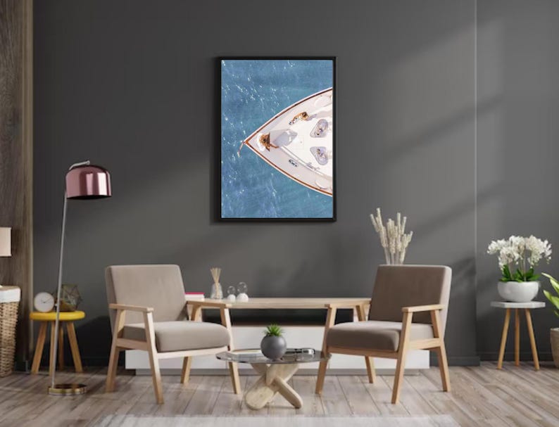 May include: A photograph of a white sailboat with a wooden bow, viewed from above, floating on a blue body of water. The boat is surrounded by blue water with whitecaps.