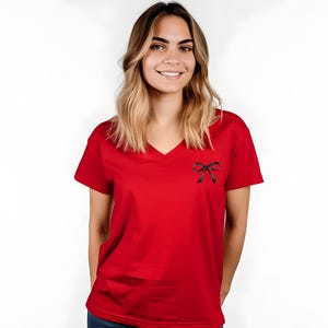 May include: A red v-neck t-shirt with a black bow on the front.