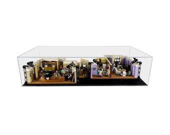 May include: A clear acrylic display case with a black base, showcasing a detailed LEGO replica of the iconic "Friends" apartment set. The set includes miniature figures of the six main characters and various props from the show.