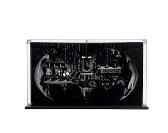 May include: A black LEGO Batman Batcave set displayed in a clear acrylic display case. The Batcave is built into the shape of the Batman logo. The set includes minifigures of Batman, Robin, and other characters.