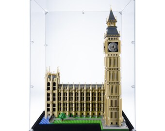 May include: A detailed Lego model of the Big Ben clock tower and the Houses of Parliament, displayed inside a clear acrylic case. The model features tan and gray bricks, with a black base and a green and blue landscape.