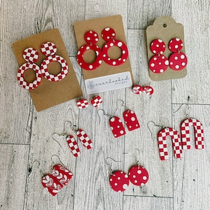 Peut inclure: Assortiment de boucles d'oreilles en argile polymère rouge et blanche. Les boucles d'oreilles présentent différentes formes et motifs, notamment des pois, des carreaux et des motifs floraux. Les boucles d'oreilles sont faites à la main et ont des crochets argentés.