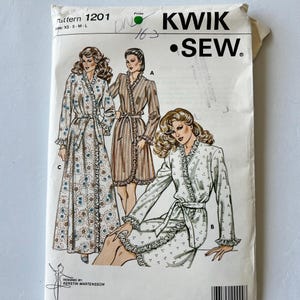 Könnte beinhalten: Ein Vintage-Schnittmuster von Kwik Sew, Muster 1201, mit Illustrationen von drei verschiedenen Morgenmänteln. Das Muster umfasst die Größen XS bis L. Das Cover ist weiß mit Text und Illustrationen in Schwarz, Braun und Blau.