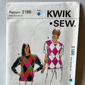 May include: A vintage sewing pattern labelled "Kwik Sew 2186." The pattern shows illustrations of two tops with diamond-shaped colour block designs. Sizes available are XS-S-M-L-XL. The pattern is printed on white paper.