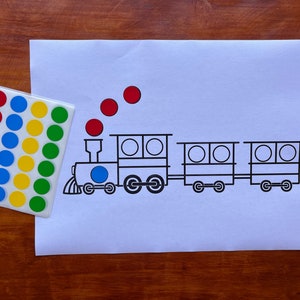 May include: A printable train activity for kids. The image shows a black and white outline of a train with four cars. There are four red circles above the train. A sheet of stickers with red, blue, yellow, and green circles is in the lower left corner of the image.