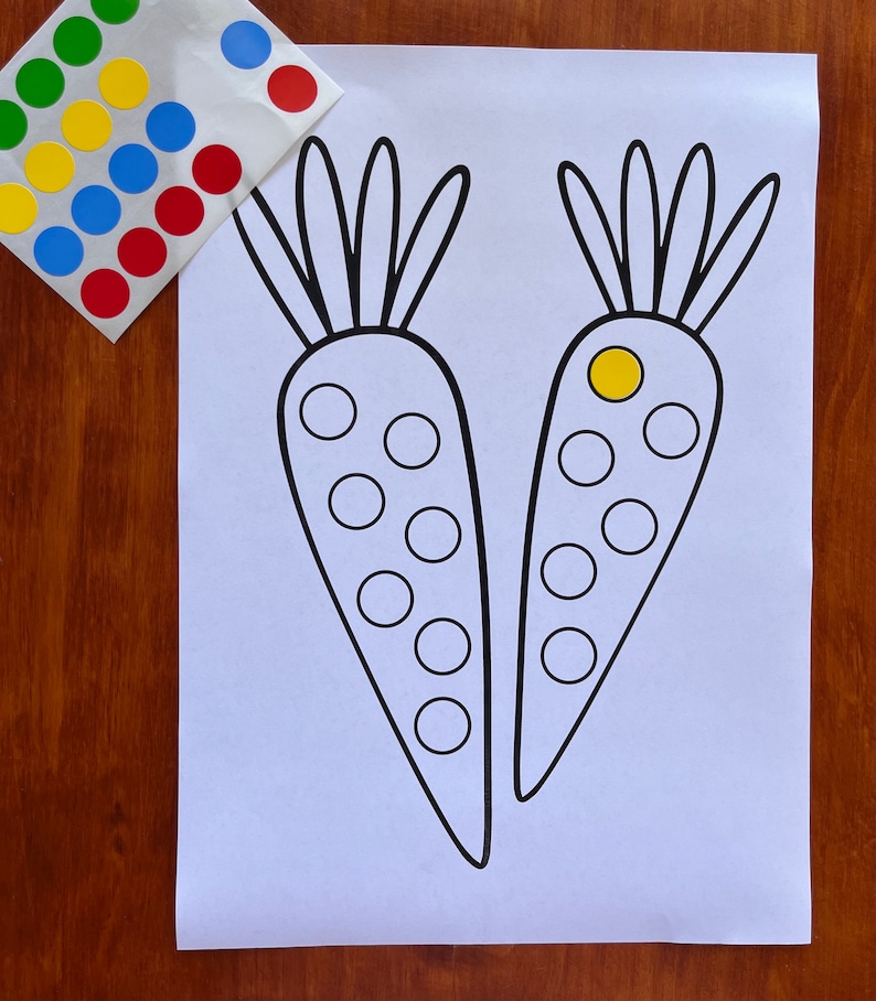K&ouml;nnte beinhalten: Ein ausdruckbares Arbeitsblatt mit zwei schwarzen und wei&szlig;en Umrissen von Karotten. Jede Karotte hat 10 Kreise, die Kinder mit bunten Aufklebern ausf&uuml;llen k&ouml;nnen.