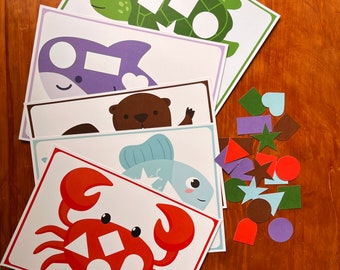 May include: A set of five printable activity cards featuring various sea creatures, including a turtle, a dolphin, an otter, a fish, and a crab. Each card has a shape cutout for children to match with the corresponding shape from a separate set of colorful shapes.