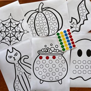 Könnte beinhalten: Fünf schwarz-weiße Halloween-Malvorlagen mit Punkten zum Verbinden, die eine Spinne, einen Kürbis, einen Kessel, ein Gespenst und eine Katze zeigen. Jedes Blatt hat eine Vielzahl von Kreisen, die mit bunten Punkt-Stickern ausgefüllt werden können.