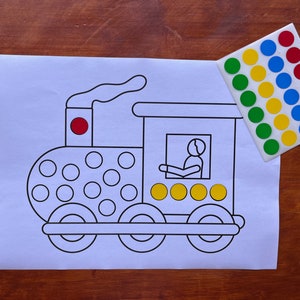 May include: A black and white outline of a train with a red circle on the top of the engine. There are 18 circles on the side of the train, 4 circles in the window, and 4 circles on the back of the train. There are 27 colorful stickers on a white sheet of paper.